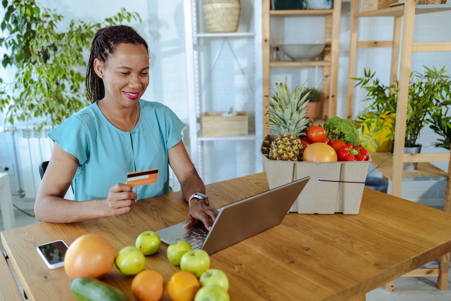 Femme afro-américaine utilisant des services de livraison d’aliments biologiques et payant par carte de crédit