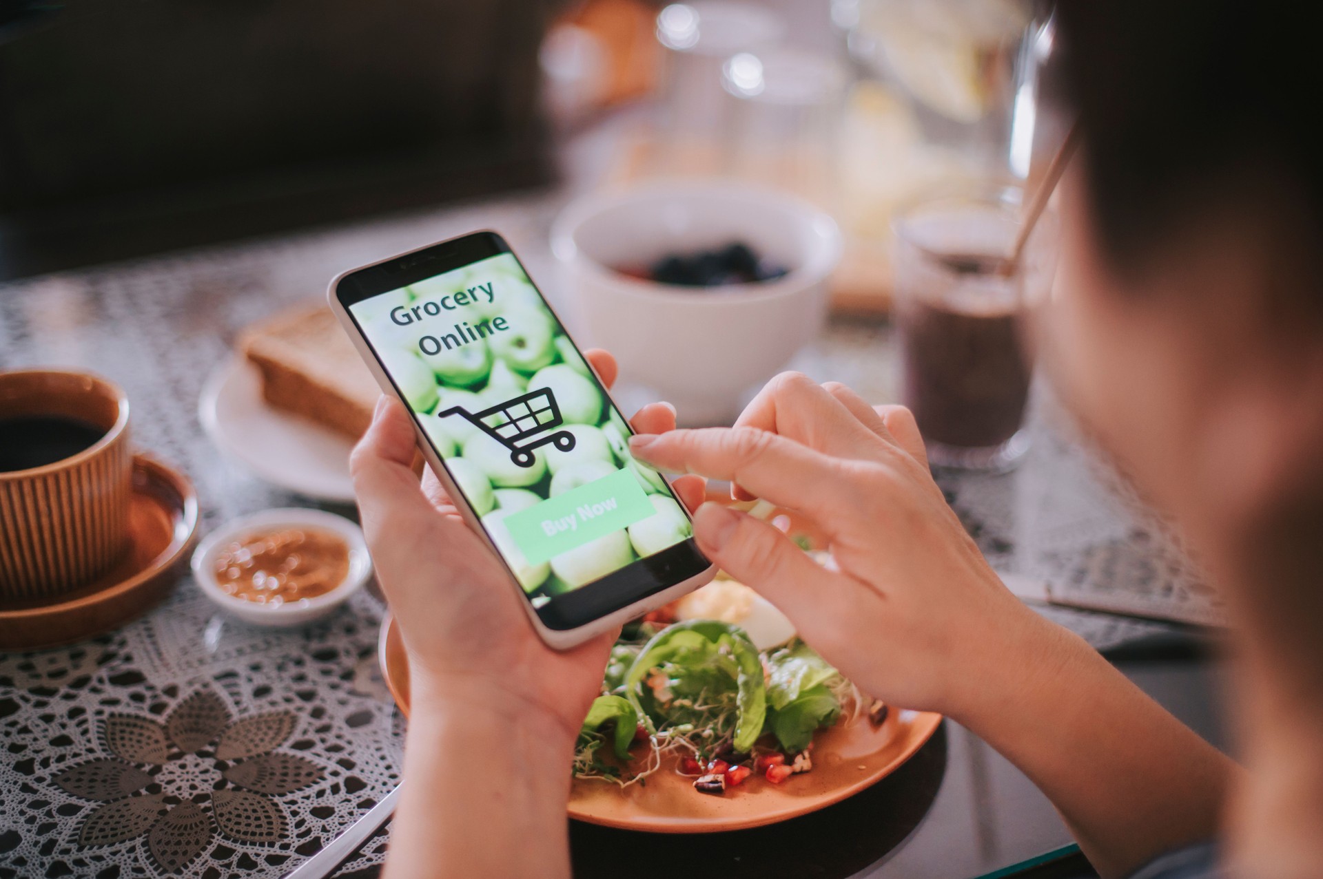 vue à angle élevé main asiatique de femme chinoise sur l’application mobile pour la livraison en ligne d’aliments d’épicerie pendant le temps de petit déjeuner
